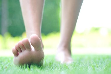 Kadın bacağı yere düştü. O, sabahleyin egzersiz yapmak için çimenlerde yürümek üzeredir. Sağlık ve Rahatlama Konseptleri