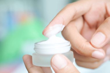 Nemlendirici krem ve serum tutan kadının eli. Yüz kremi sürüyor, cilt bakımı için yağ, losyon ve vücut kremi, yakın görüş ve bulanık arka plan. Güzellik ve Sağlık Konsepti.