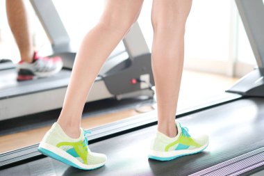 Spor salonunda koşu bandında koşan kadının bacağı koşu ayakkabılarıyla atletik koşuyor. Sağlık ve spor konsepti geçmişi,