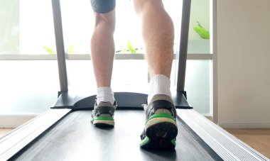 Spor salonunda koşu bandında koşan bir adamın bacağı koşu ayakkabılarıyla atletik koşuyor. Sağlık ve spor konsepti geçmişi,