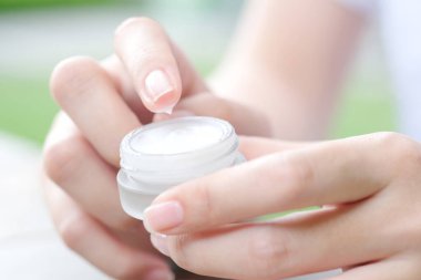Nemlendirici krem ve serum tutan kadının eli. Yüz kremi sürüyor, cilt bakımı için yağ, losyon ve vücut kremi, yakın görüş ve bulanık arka plan. Güzellik ve Sağlık Konsepti.