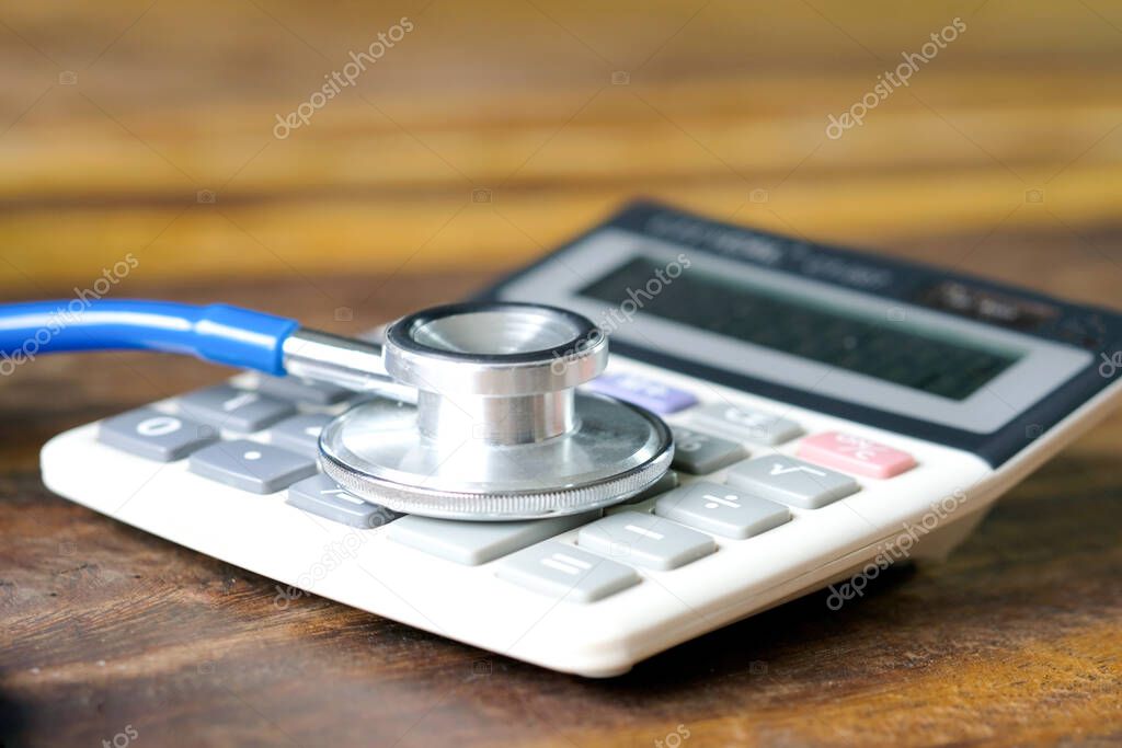 Medical expense concept , Accident Insurance or Health Insurance. Put stethoscope on a calculator with wooden background. Fee Protection Concept.