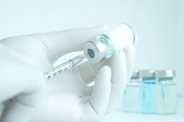 Şırınga ve ilaç şişesini tutan doktorun eli. Enjeksiyon için hazırlanılıyor