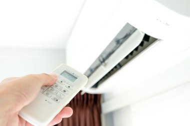 Adamın eli uzaktan kumanda ile açılıyor klima yatak odasında 25 santigrat dereceye kadar soğutuluyor. Sağlık kavramları ve enerji tasarrufları
