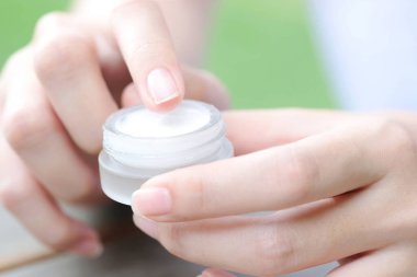 Nemlendirici krem ve serum tutan kadının eli. Yüz kremi sürüyor, cilt bakımı için yağ, losyon ve vücut kremi, yakın görüş ve bulanık arka plan. Güzellik ve Sağlık Konsepti.