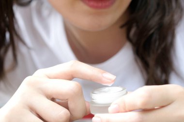 Nemlendirici krem ve serum tutan kadının eli. Yüz kremi sürüyor, cilt bakımı için yağ, losyon ve vücut kremi, yakın görüş ve bulanık arka plan. Güzellik ve Sağlık Konsepti.