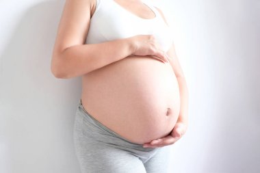 Onun bir bebeği var. Kadın hamile. Anne ve bebeğe duyulan sevgiyle karnına dokunuyor. Aile kavramı, sağlık kavramı boyunca ilişki.