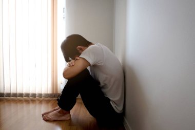 Odanın köşesinde oturan adam mutsuzdu.