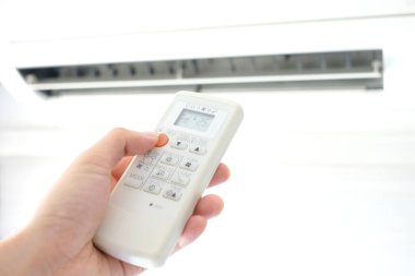 Adamın eli uzaktan kumanda ile açılıyor klima yatak odasında 25 santigrat dereceye kadar soğutuluyor. Sağlık kavramları ve enerji tasarrufları