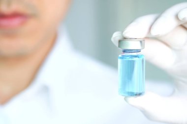 doctor's hand, he holds a bottle of antiretroviral drugs, blue water.