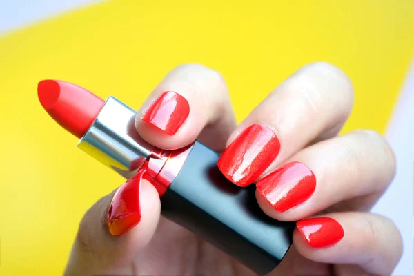 Nail red of a beautiful woman and holding a red lipstick.on colorful background .Beauty concept