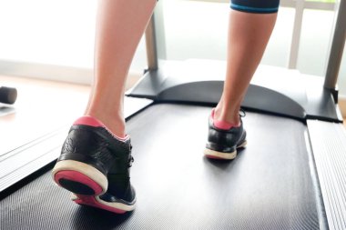 Spor salonunda koşu bandında koşan kadının bacağı koşu ayakkabılarıyla atletik koşuyor. Sağlık ve spor konsepti geçmişi,