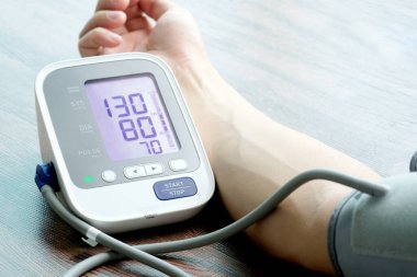 Man checks blood pressure monitor and heart rate monitor with digital pressure gauge. Health care and Medical concept.