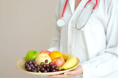 The hands of a healthy nutritionists, she holds a bowl with fruits, apples, grapes and avocados.