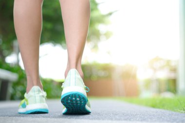 Koşu ayakkabılarıyla atletik koşan kadın bacağı sabah egzersiz yapmak için yerdedir. Sağlık ve Rahatlama Konseptleri. Sağlıklı yaşam tarzı