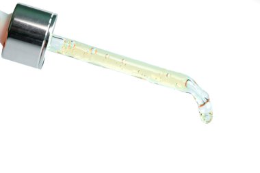 Güzel bir kadının elleri, yüzüne serum kolajen nemlendirici dökerek berrak sarı şişe yumuşak ışık arka planına döküyor. Koruyucu cilt bakımı yüz özü yağı, C vitamini güzellik ve kaplıca.