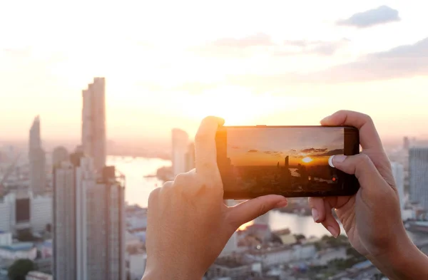 Gençler şehirdeki binaların fotoğraflarını çekiyor. Gün doğumu zamanı. Yüksek açılı bir fotoğraf telefonu kullanıyor. Seyahat kavramları ve teknoloji.