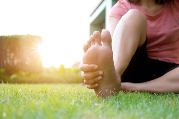 足の痛み彼は足を保持し 朝の日差しの中で筋肉を伸ばす公園で草の上に座っている男の足 ヘルスケアとスパのコンセプト — ストック写真
