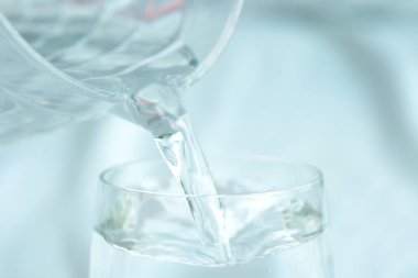 Sağlıklı olmak için temiz su. Atıcı 'dan bardağa temiz su dökerek masa tahtasına dökülüyor. Sağlık ve Diyet Konsepti. Yaşam Tarzı Sağlık ve Güzellik.