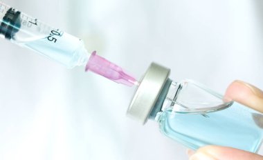 Doktorun elinde hastanede bir şırınga ve mavi bir aşı şişesi var. Sağlık ve tıbbi kavramlar