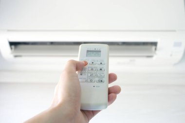 Adamın eli uzaktan kumanda ile açılıyor klima yatak odasında 25 santigrat dereceye kadar soğutuluyor. Sağlık kavramları ve enerji tasarrufları