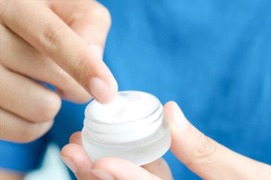 Nemlendirici krem ve serum tutan kadının eli. Yüz kremi sürüyor, cilt bakımı için yağ, losyon ve vücut kremi, yakın görüş ve bulanık arka plan. Güzellik ve Sağlık Konsepti.