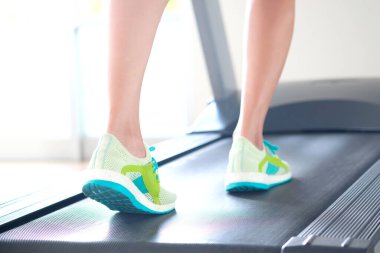 Spor salonunda koşu bandında koşan bir kadın koşu ayakkabısıyla atletik koşuyor. Sağlık ve spor konsepti