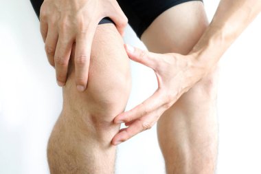 Diz ağrısı. Kadın çimlerin üzerinde duruyor. Eli dizinden sıkıştı. Acıyı dindirmek için ayaklarının ağrıması ve kaslarının yorulması. sağlık kavramları.