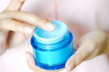 Nemlendirici krem ve serum tutan kadının eli. Yüz kremi sürüyor, cilt bakımı için yağ, losyon ve vücut kremi, yakın görüş ve bulanık arka plan. Güzellik ve Sağlık Konsepti.