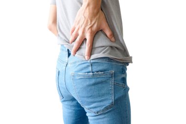 The young man has back pain, holding his hand on his waist and back.