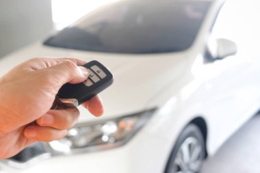 Uzaktan kumandayı tutan adam, arabanın kapısını açmak için uzaktan kumandaya basıyor.