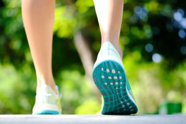 Koşu ayakkabılarıyla atletik koşan kadın bacağı sabah egzersiz yapmak için yerdedir. Sağlık ve Rahatlama Konseptleri. Sağlıklı yaşam tarzı