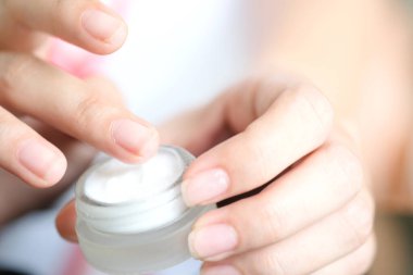 Nemlendirici krem ve serum tutan kadının eli. Yüz kremi sürüyor, cilt bakımı için yağ, losyon ve vücut kremi, yakın görüş ve bulanık arka plan. Güzellik ve Sağlık Konsepti.