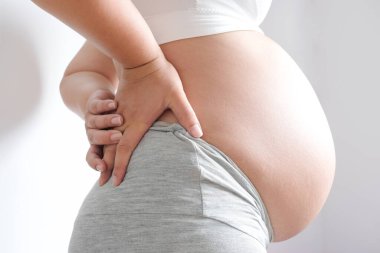 Woman is pregnant  belly Use hands to hold back pain in the back. , Health concept.