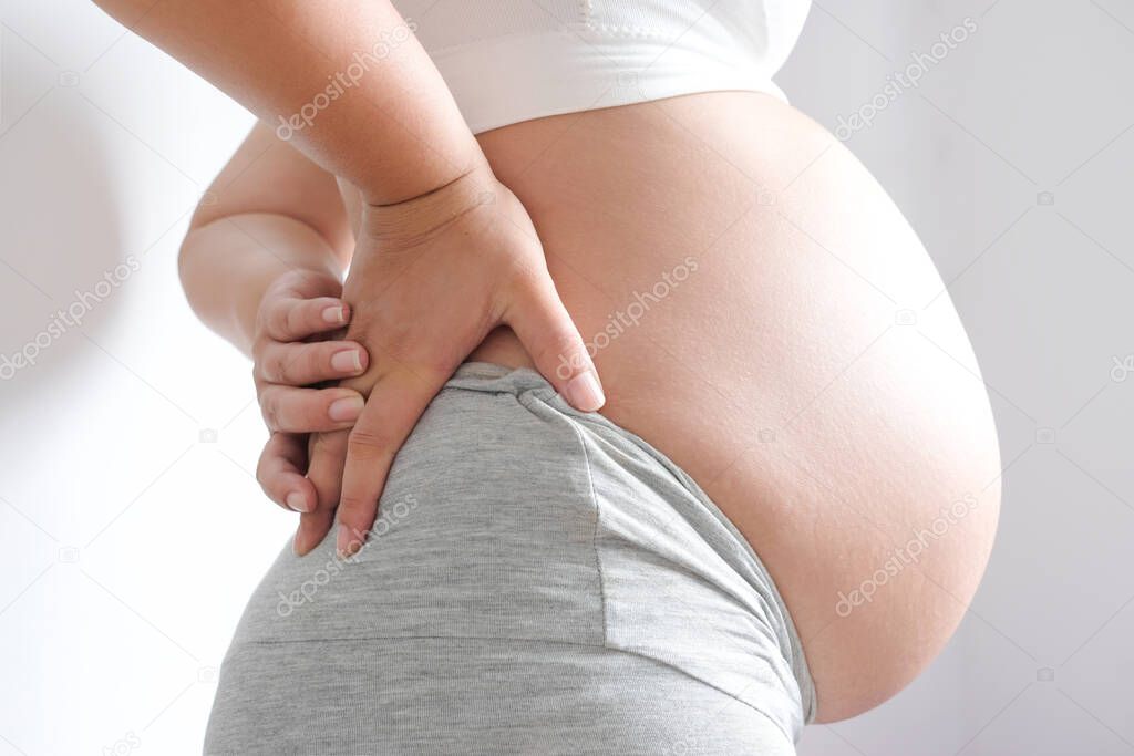 Woman is pregnant  belly Use hands to hold back pain in the back. , Health concept.
