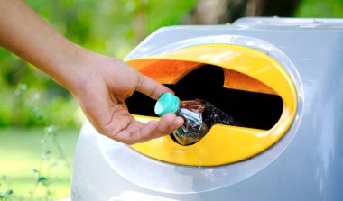 Lütfen plastik şişeyi depoya atın. Bir adam çöp tenekesine çöp atar gibi çöp atmak için çöpleri ayırır. ,