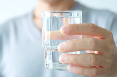 Sabah, bir adamın eli içmek için temiz bir bardak su tutuyor..