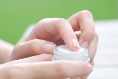 Nemlendirici krem ve serum tutan kadının eli. Yüz kremi sürüyor, cilt bakımı için yağ, losyon ve vücut kremi, yakın görüş ve bulanık arka plan. Güzellik ve Sağlık Konsepti.