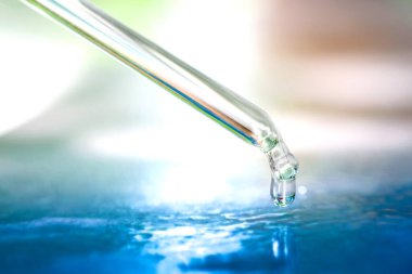 Dropping serum collagen moisturizer of face on water sea blue background. Protector skin Treatment facial essence oil, Vitamin C. Beauty and spa Concept