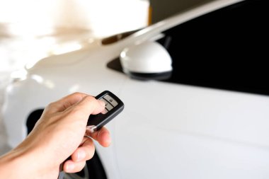 Uzaktan kumandayı tutan adam, arabanın kapısını açmak için uzaktan kumandaya basıyor.