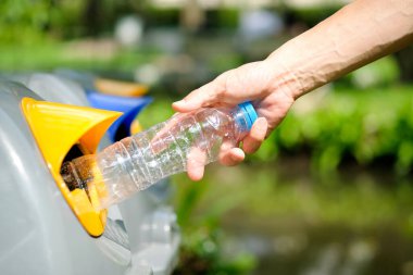 Lütfen plastik şişeyi depoya atın. Bir adam çöp tenekesine çöp atar gibi çöp atmak için çöpleri ayırır. ,