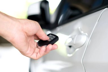 Uzaktan kumandayı tutan adam, arabanın kapısını açmak için uzaktan kumandaya basıyor.