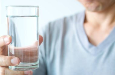 Sabah, bir adamın eli içmek için temiz bir bardak su tutuyor..