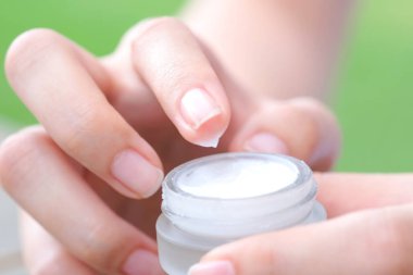 Nemlendirici krem ve serum tutan kadının eli. Yüz kremi sürüyor, cilt bakımı için yağ, losyon ve vücut kremi, yakın görüş ve bulanık arka plan. Güzellik ve Sağlık Konsepti.