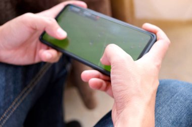 Genç bir adamın elleri, akıllı telefon kullanır ve akıllı telefondan oyun oynar..