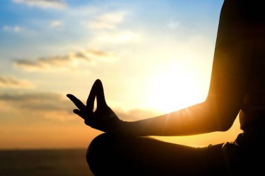 Sabah saatlerinde deniz sahillerinde meditasyon yapan bir kadının silüeti..