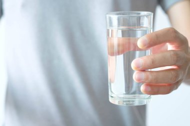 Sabah, bir adamın eli içmek için temiz bir bardak su tutuyor..