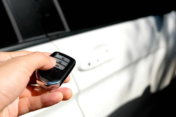 Man hand holding the car remote, he push the remote control to open the car door