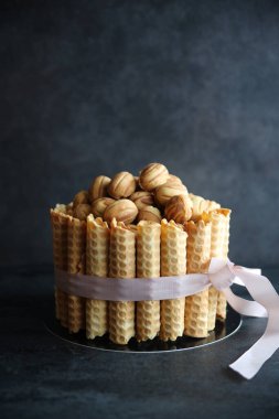 Bu ikonik Rus ballı keki nam-ı diğer Tort Medovik. En lezzetli kremayla doldurulmuş bal üstüne bal katmanları. İçinde yoğun süt ve ceviz parçalarıyla dolu waffle ruloları ve fındıklarla süslenmiş..