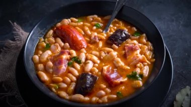 Geleneksel fasulye tarifi sucuklu ve kanlı sosis Fabada Asturiana adında karanlık bir masa üzerinde bazı malzemelerle birlikte. Tipik İspanyol yemekleri.. 